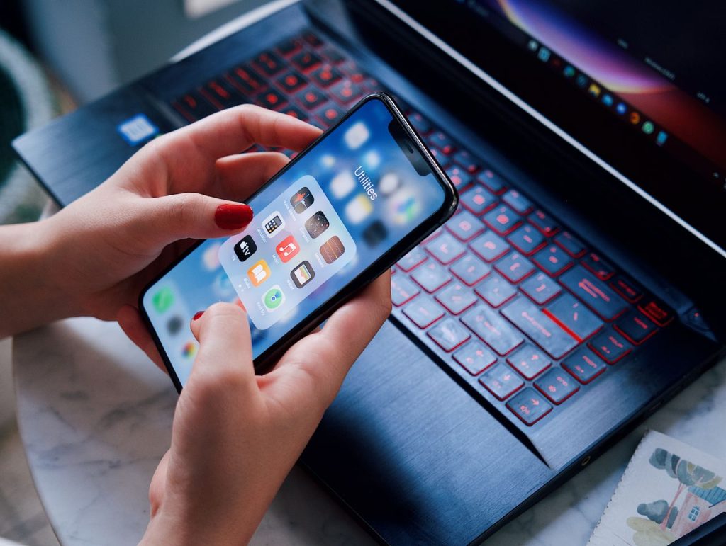 The Art of Drawing Readers In: Your attractive post title goes here Close-up of a woman using a smartphone and laptop with red keyboard in an indoor setting.