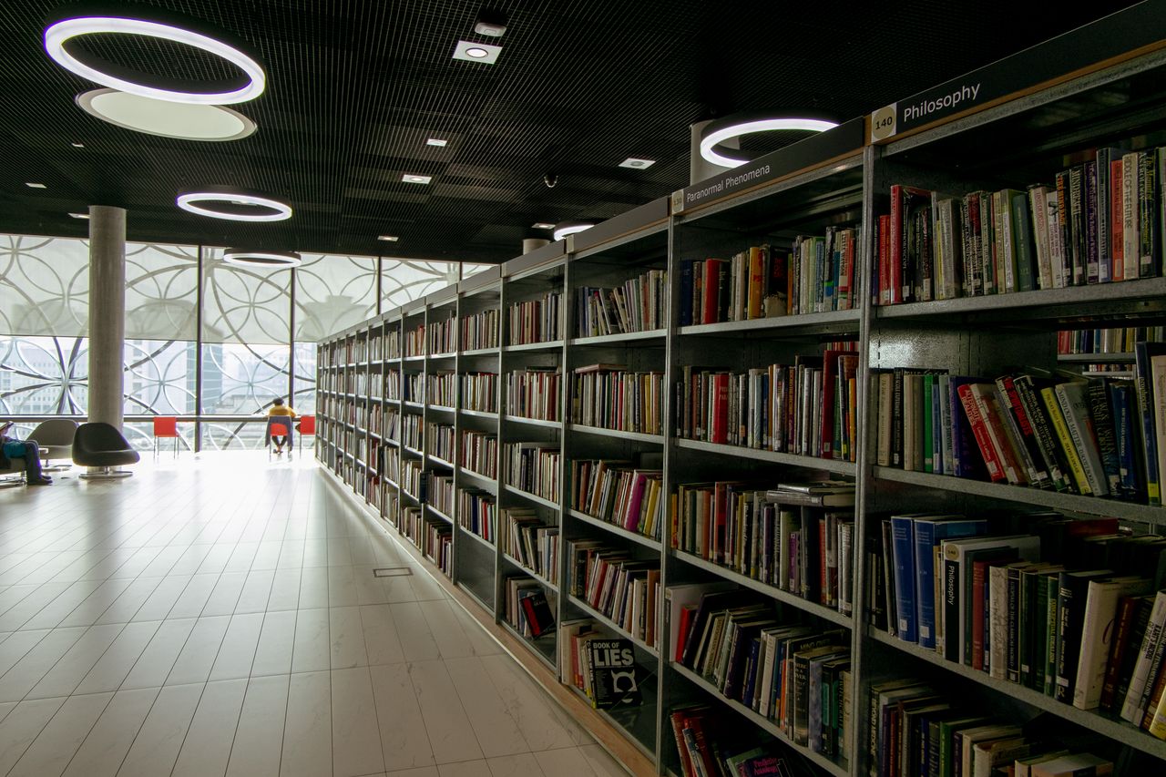 A quiet modern library interior with bookshelves and bright circular lights.
